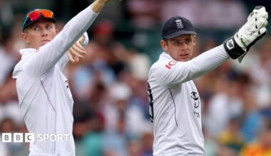 Zak Crawley on the left and wicketkeeper Jamie Smith on the right, both pointing with their right hands raised up at something off camera during the Sydney Test match