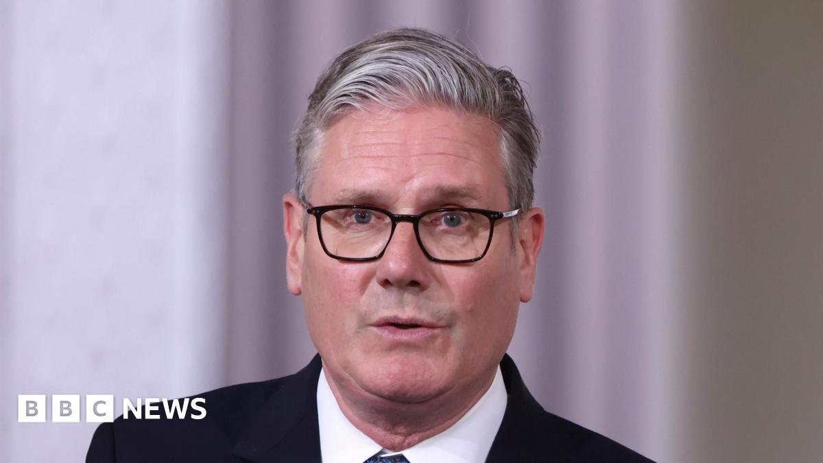 Nathan sitting in a pub with a drink. He is wearing a blue tracksuit top and has his arms crossed. He has a short beard and dark brown hair.