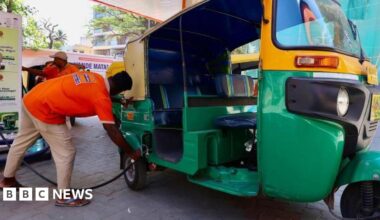 A petrol station attendant helps a customer top up his auto rickshaw in India