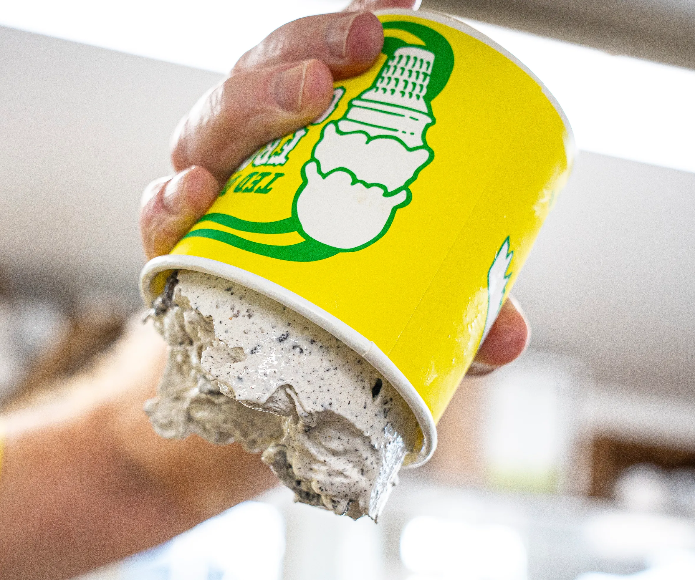 A hand holds an upside-down cup of Ted Drewes frozen custard that is not falling out.