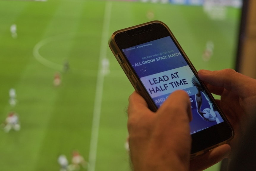 Hands holding a mobile phone displaying a gambling app.