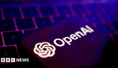 OpenAI logo displayed on a smartphone on top of a laptop keyboard.