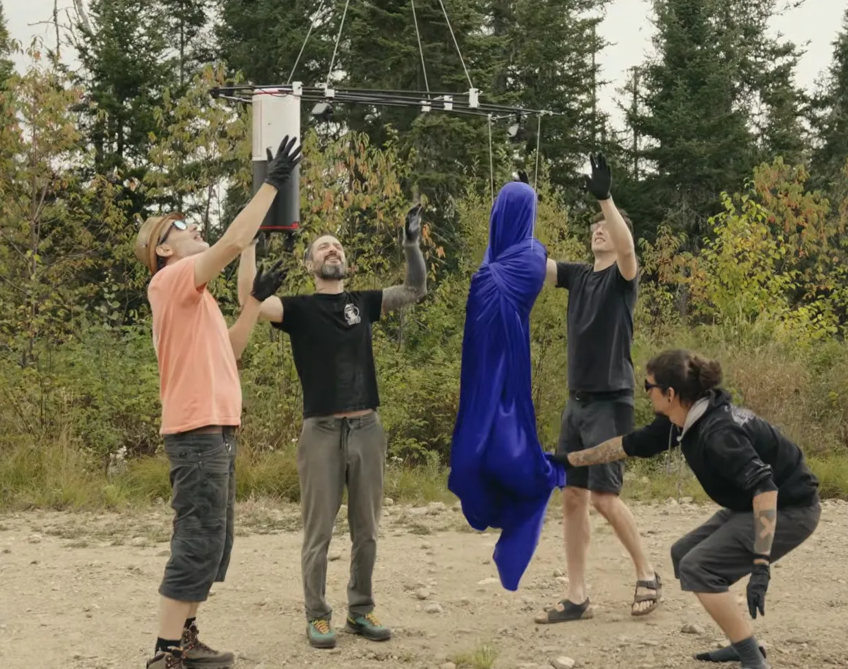 Four people preparing a silk-covered mannequin for launch into the stratosphere.