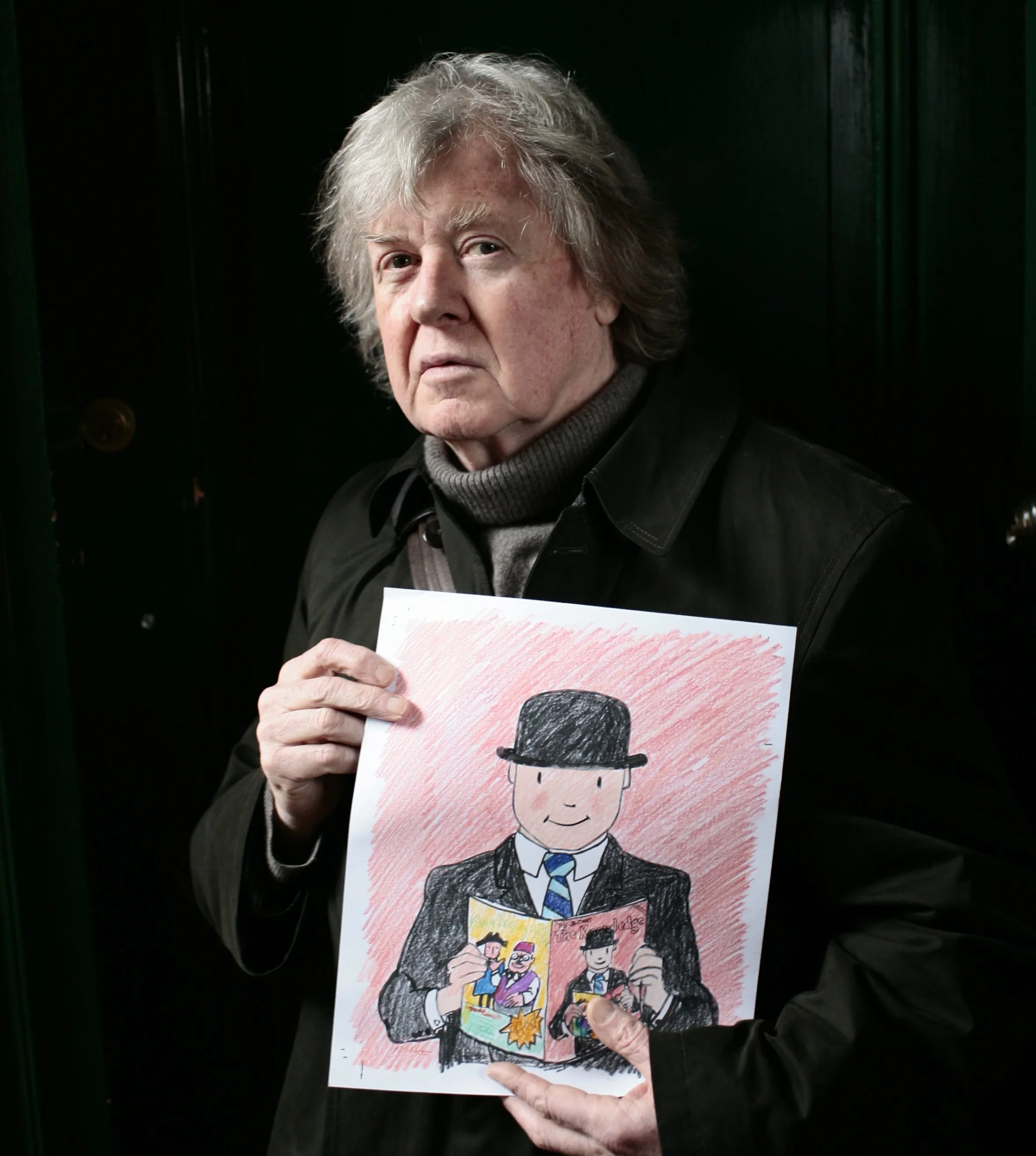 A man in a dark coat and turtleneck holds up an illustration of a man in a bowler hat reading a magazine.