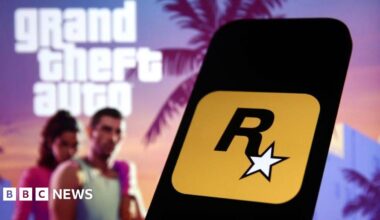 Rockstar Games logo displayed on a smartphone, against a backdrop of assets promoting GTA 6 - showing characters Lucia and Jason against a colourful sunset and palm trees.
