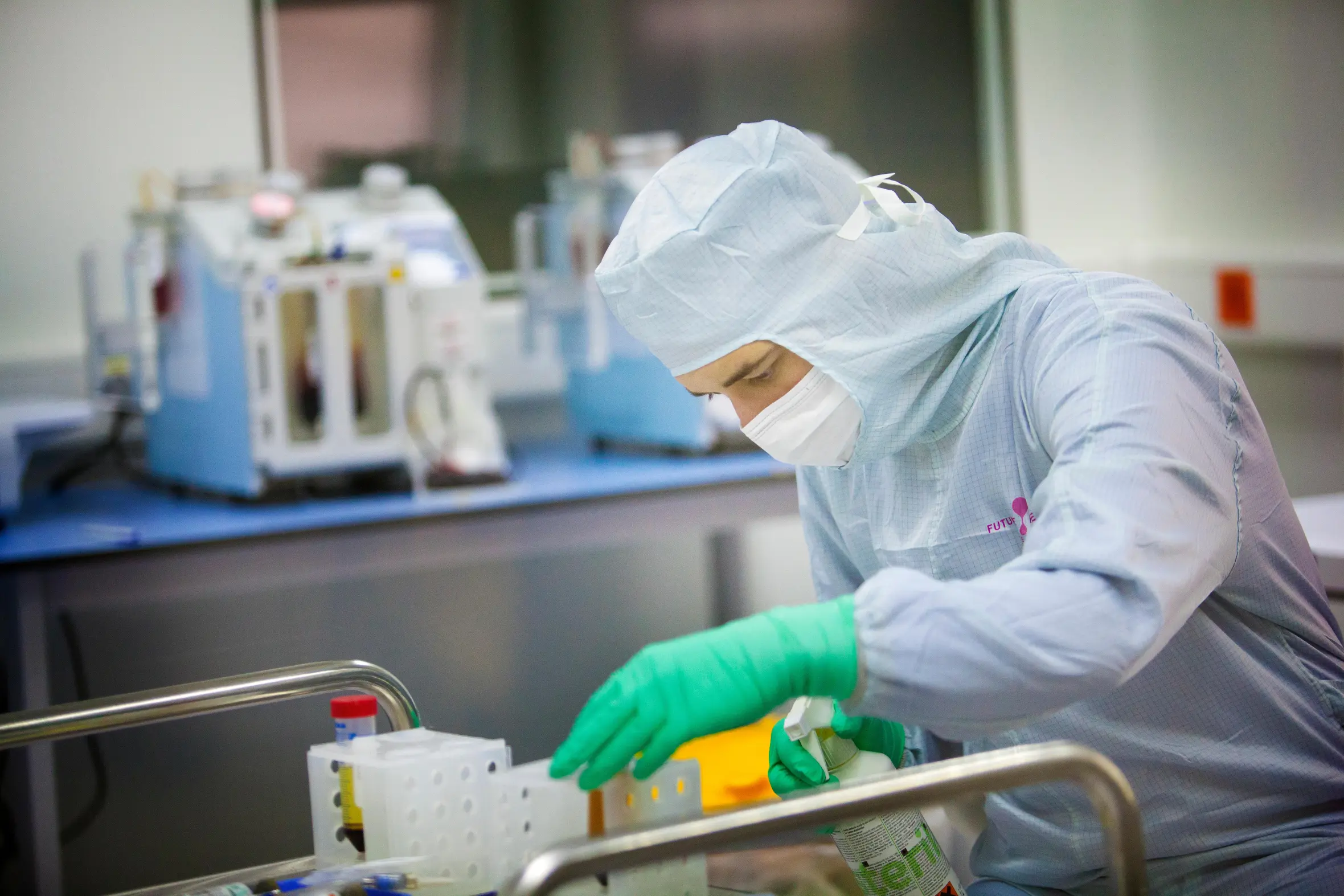 A medical professional in a sterile suit, mask, and gloves handling samples in a biobank.