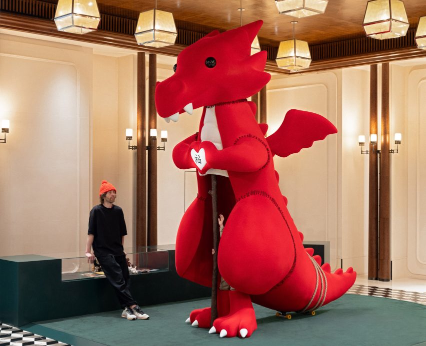 Man sitting next to red dragon on green floor