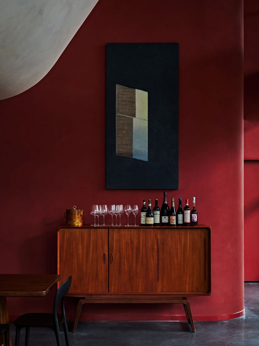 Wall painted in a paprika hue with a walnut credenza in front