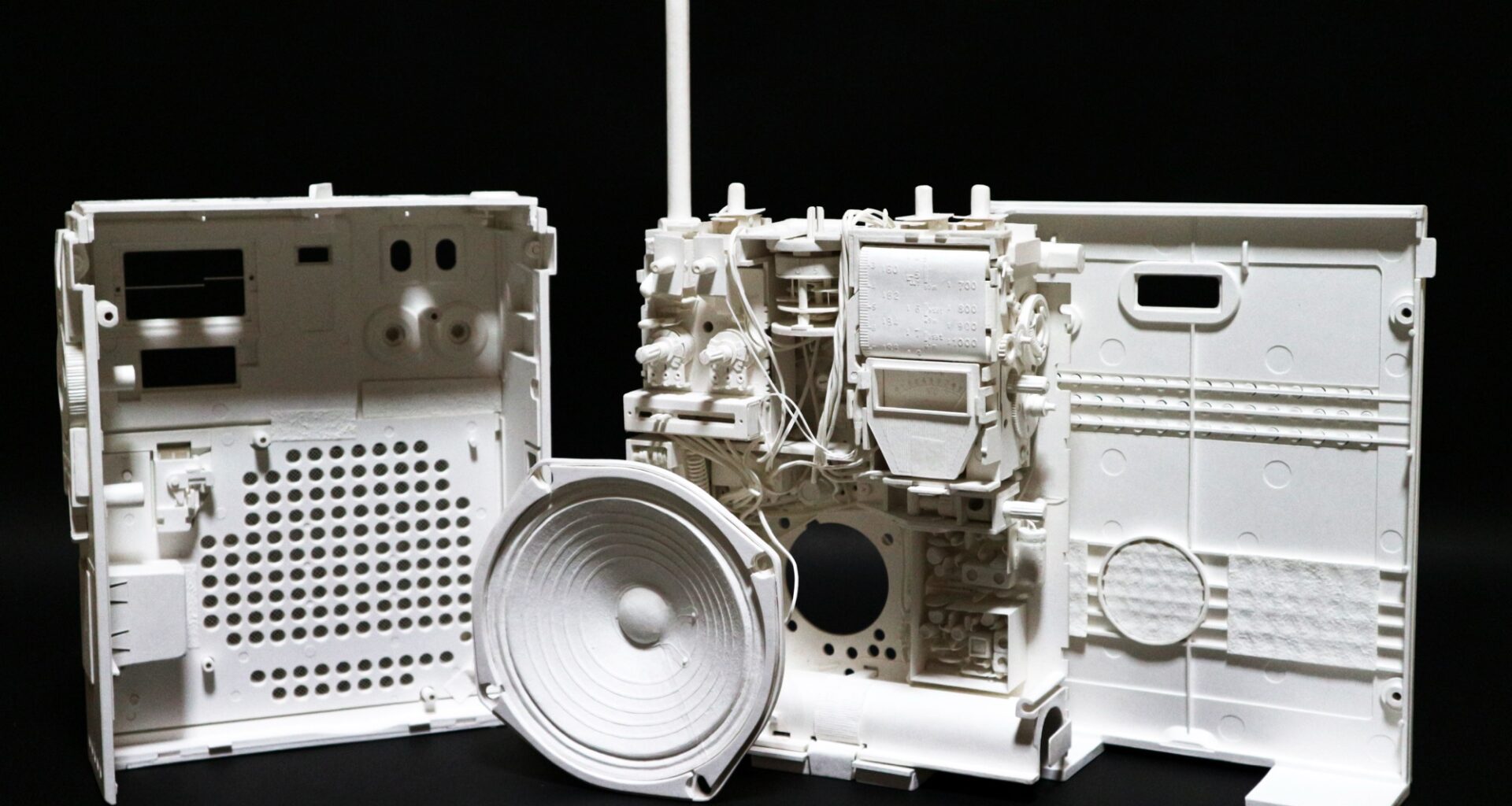 a hyperrealistic, scale sculpture of a small radio made from white paper, deconstructed to show its inner parts