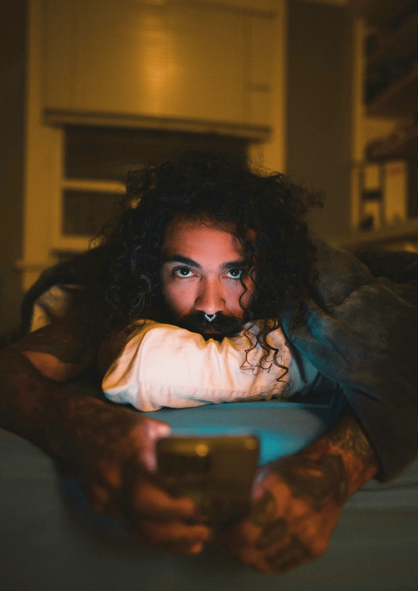 man lying in bed on his phone struggling to maintain boundaries