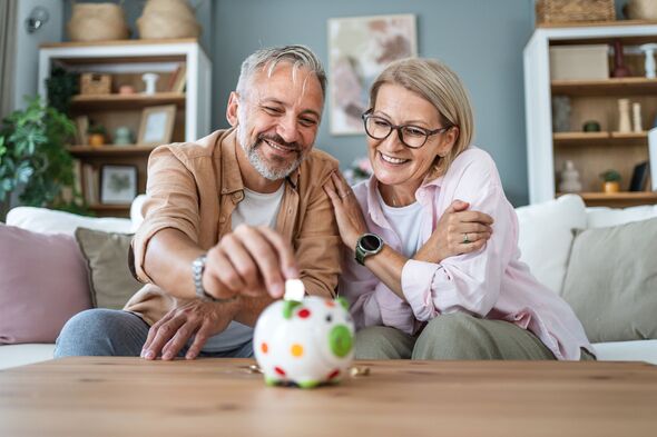 Mature couple inserting coins in a piggybank