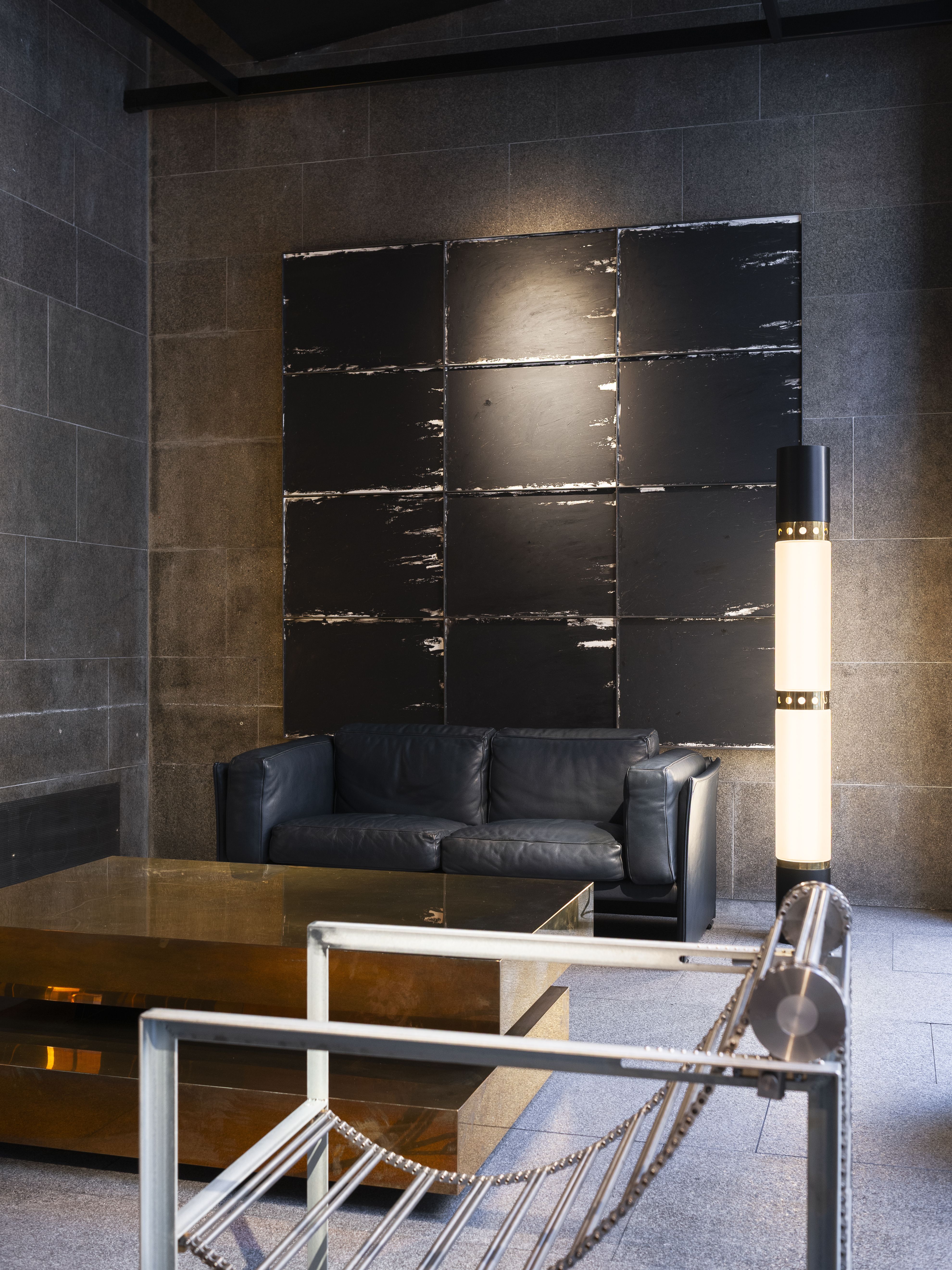 a leather sofa, bronze coffee table, and chrome chair in an industrial space