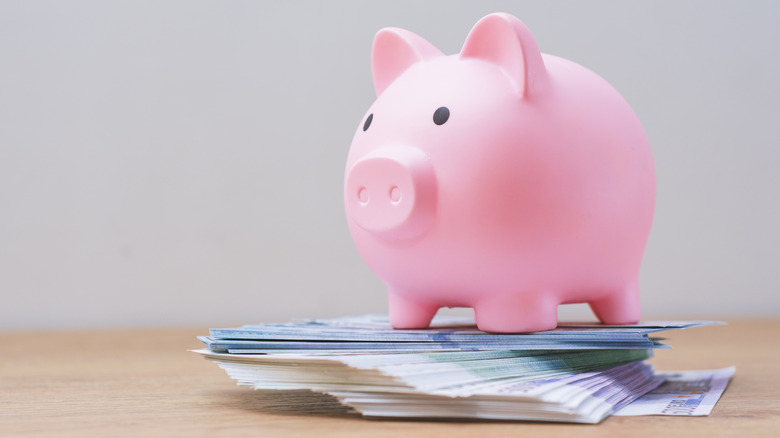 Piggy bank on top of several dollar bills