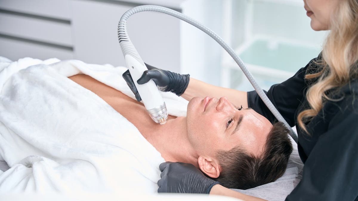 Adult man receiving microneedle RF lifting treatment in clinic.