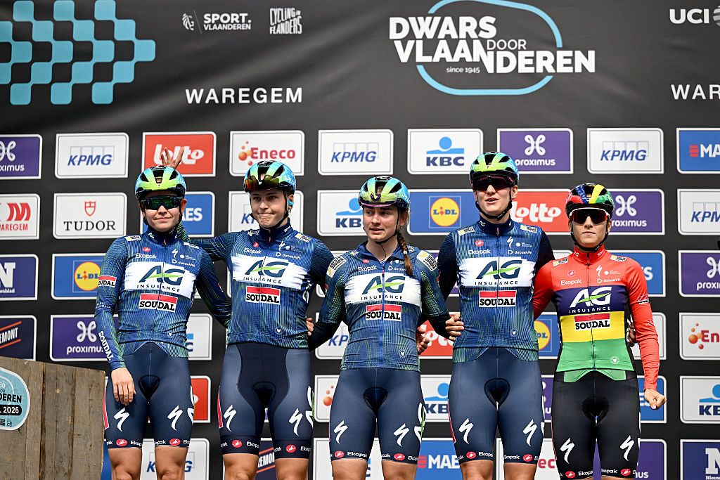 A shot of five AG Insurance-Soudal riders standing on the stage, side by side, at the sign on presentation before Dwars door Vlaanderen 2026