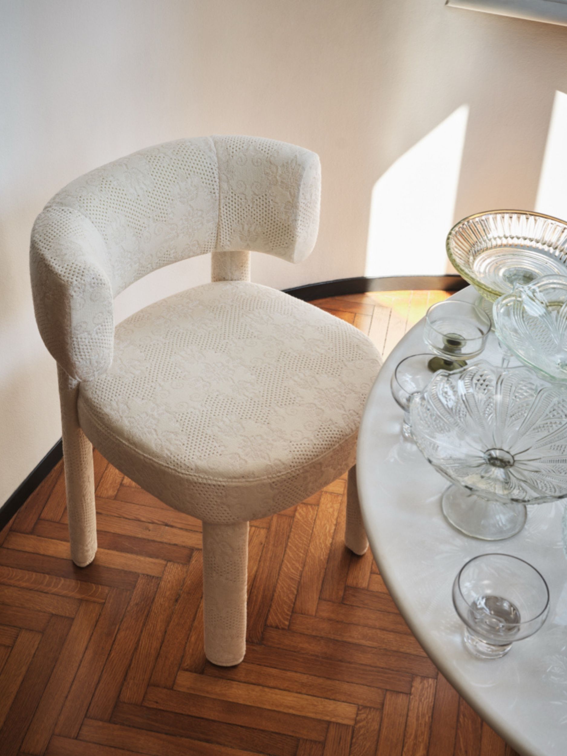 a lace covered chair at a table with glassware