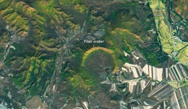 Satellite view of the horseshoe-shaped Yilan impact crater in China, showing the forested rim and central farmlands.