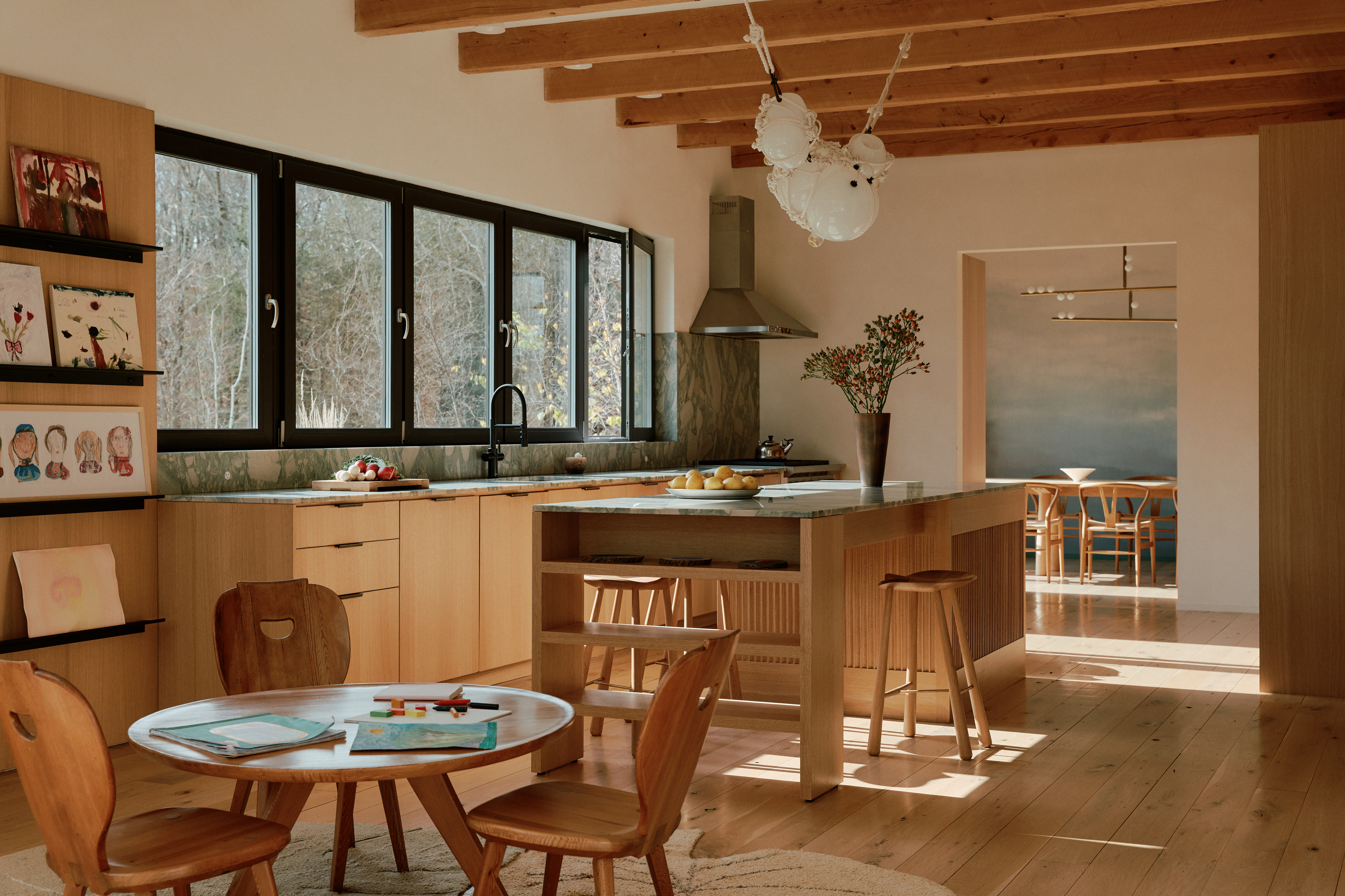 Kitchen with oak floors and kitchen furniture, vintage Alpine chairs, green marble tabletop reflects the colours outside the window.