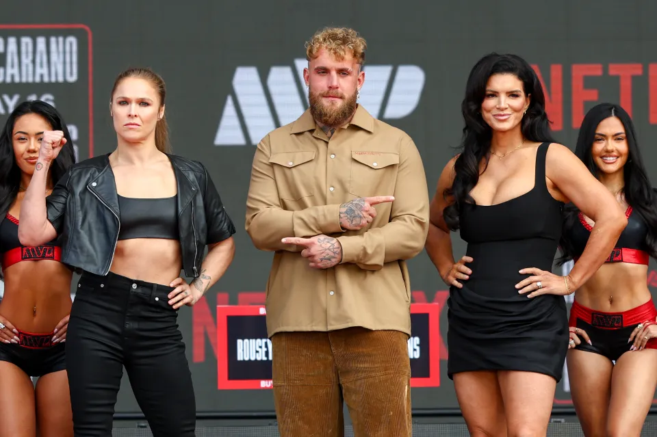 Jake Paul between Ronda Rousey and Gina Carano on stage