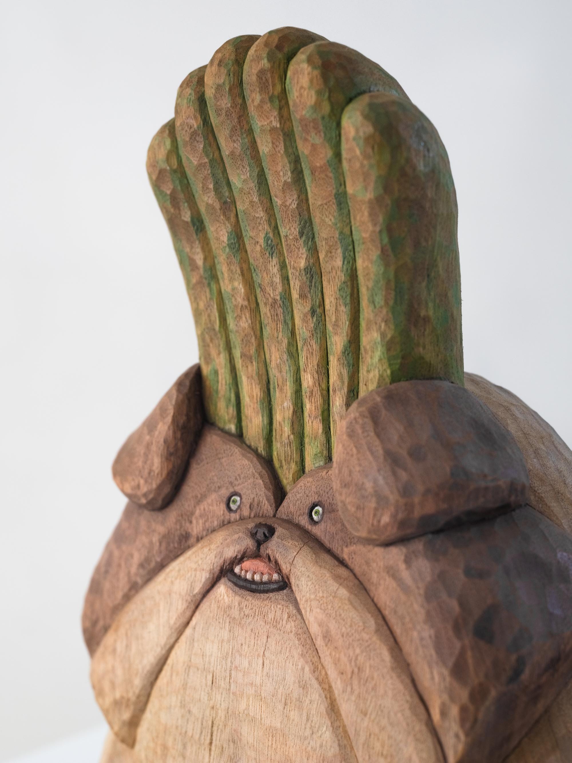 detail of a wood-carved sculpture of a dog with bamboo growing out of its head by Misato Sano