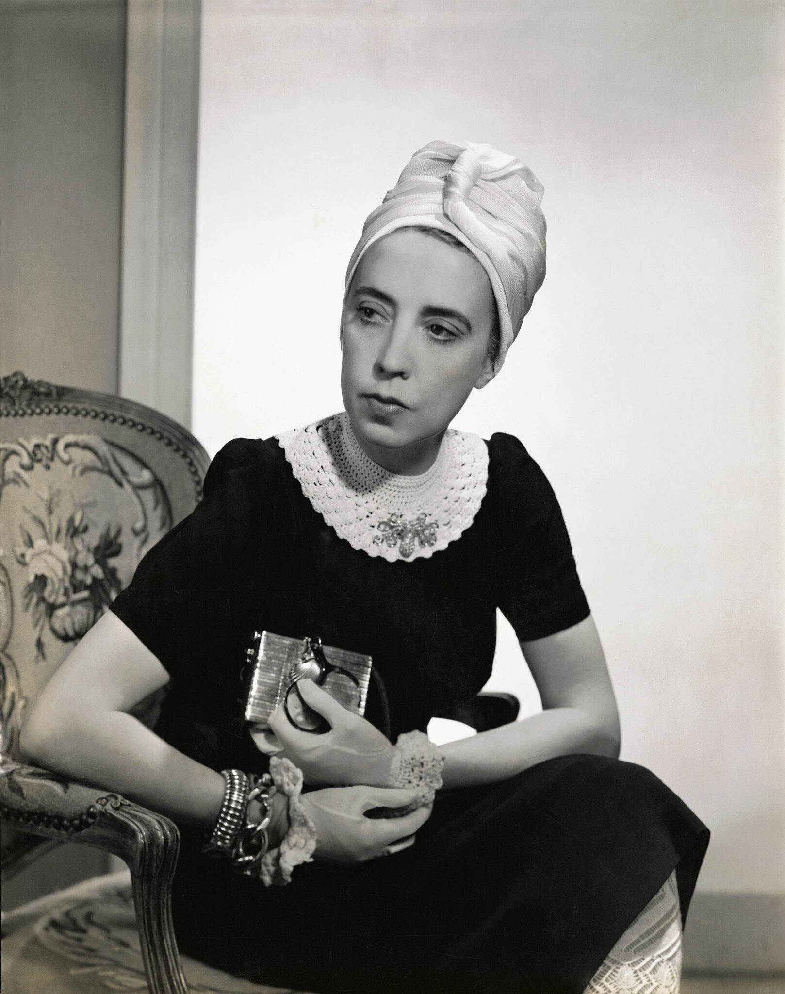 Designer Elsa Schiaparelli wearing black silk dress with crocheted collar of her own design and a tuban, as featured in Vogue in 1940