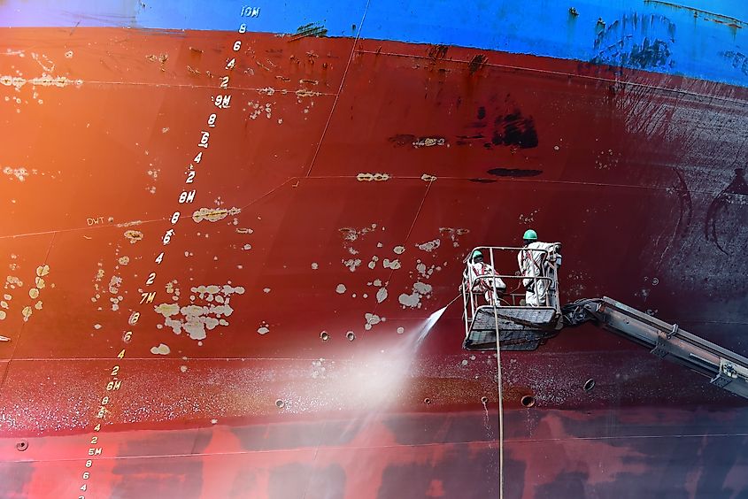 Worker cleaning and washing with Cargo ship on sherry picker car by high pressure water gun .