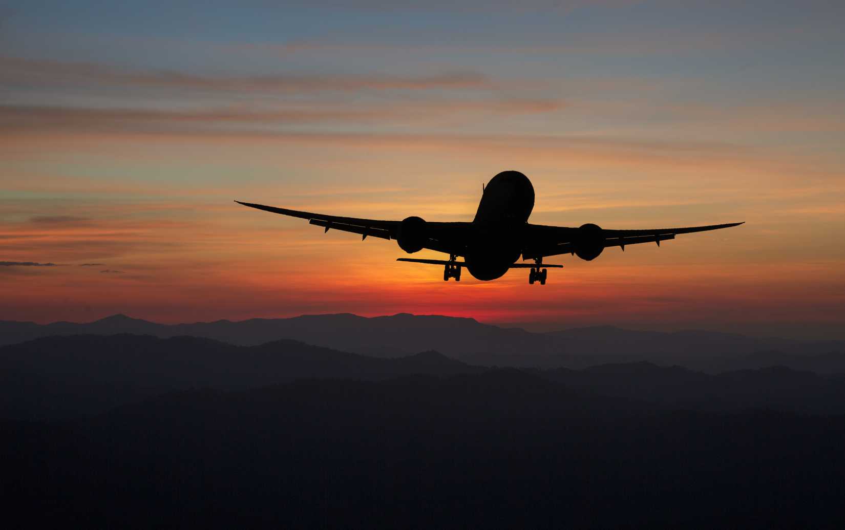 Widebody aircraft silhouetter flying across sky duirng sunset