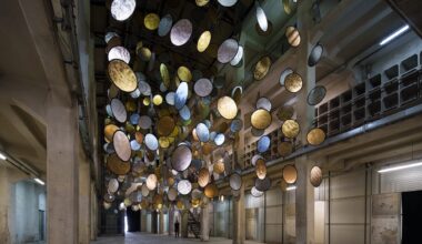 A large interior installation of metallic discs hanging from the ceiling in an industrial space
