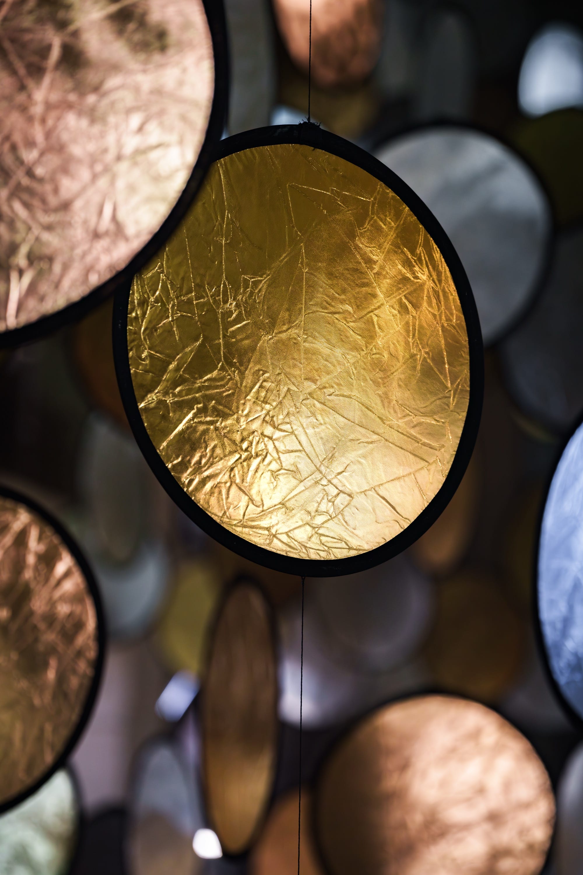 A detail of a large interior installation of metallic discs hanging from the ceiling