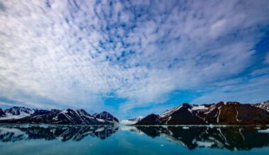 Arctic landscape with snowy mountains reflected in calm water, illustrating the Barents Sea region where Atlantic water is pushing farther into the Arctic.