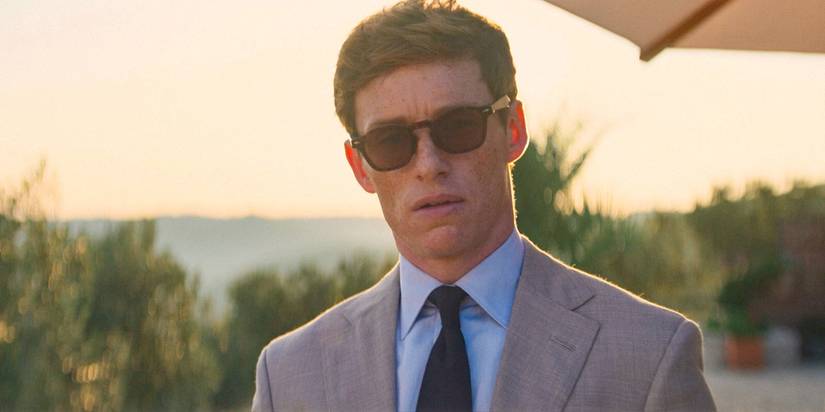 Eddie Redmayne as The Jackal looking uncertain in a suit and sunglasses in The Day of the Jackal