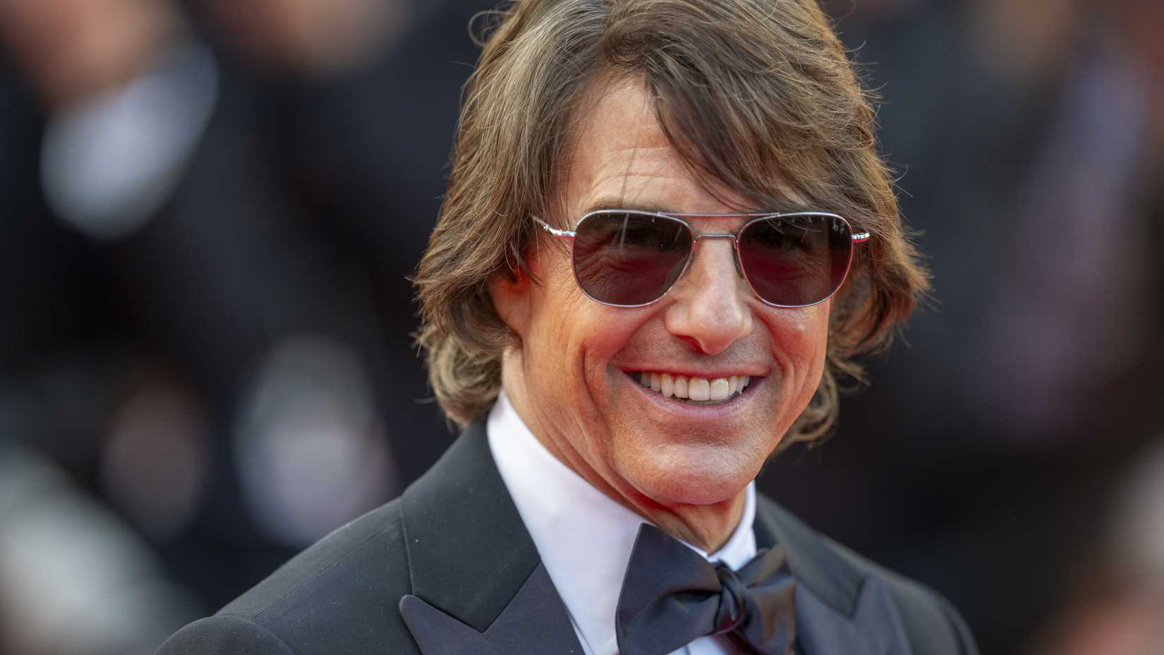 Tom Cruise smiles while walking the red carpet at an event
