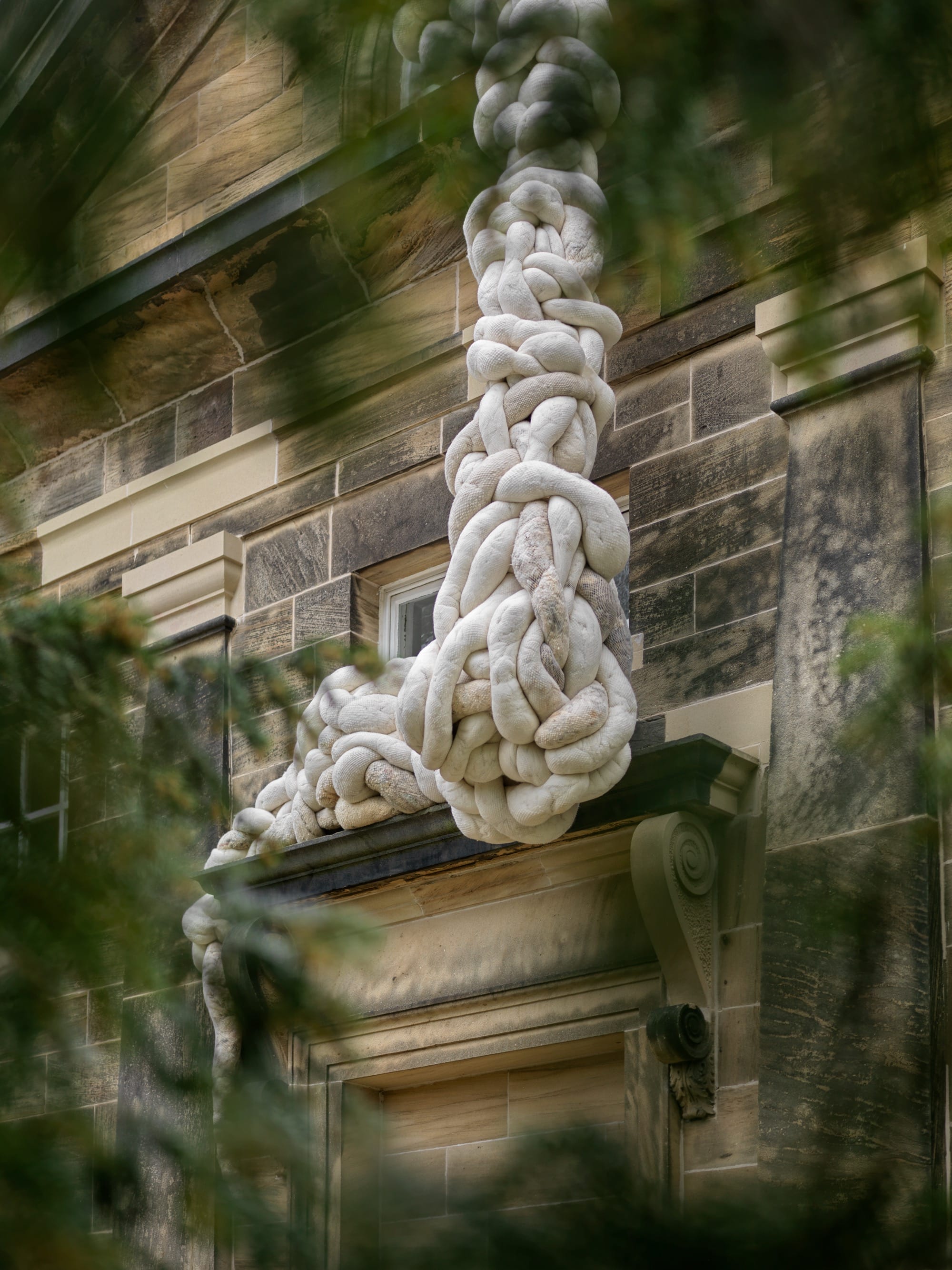 an installation view of a large-scale textile installation by Nicola Turner with undulating, twisted details that interact with a historic chapel exterior