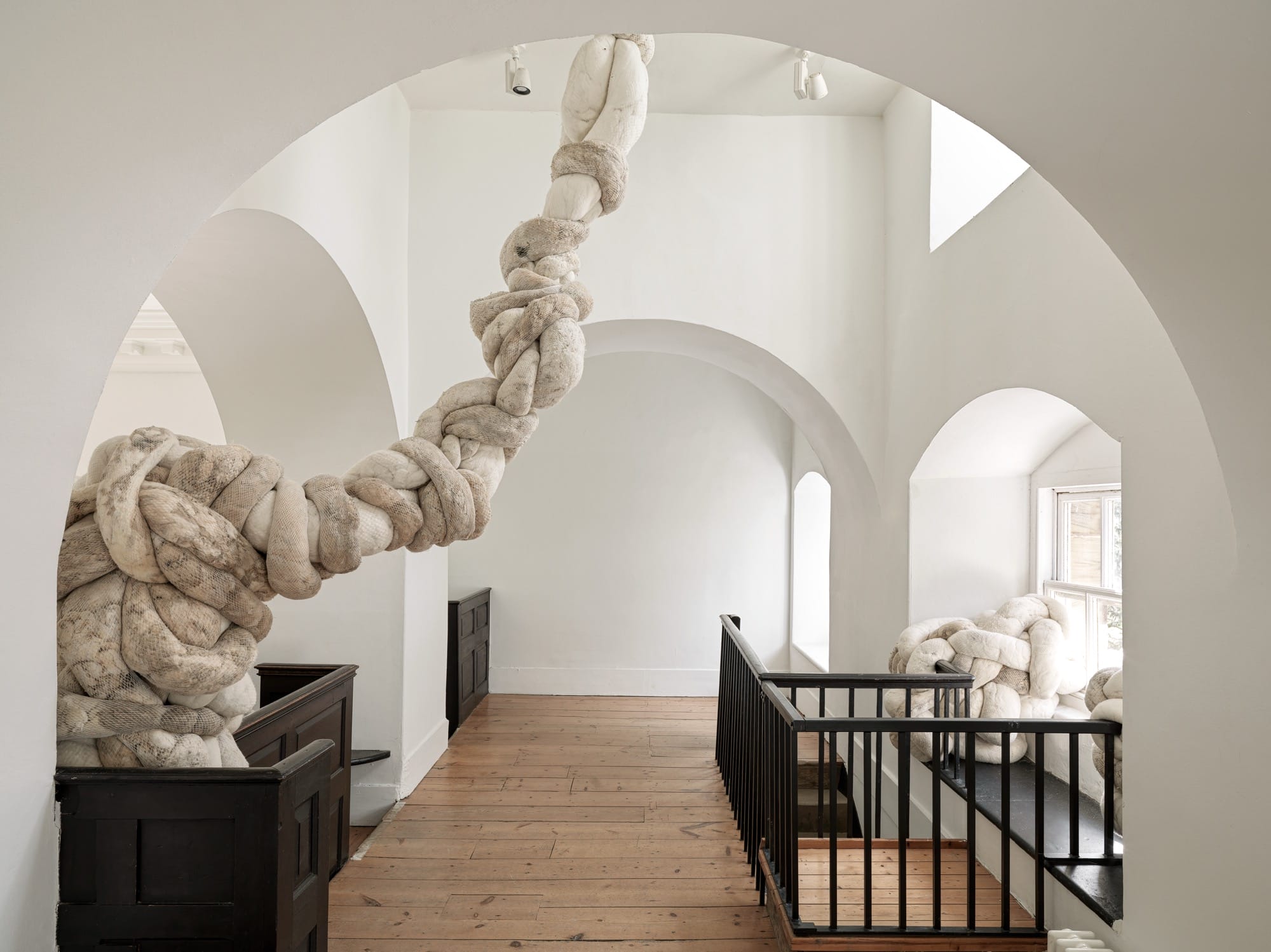 an installation view of a large-scale textile installation by Nicola Turner with undulating, twisted details that interact with a historic interior