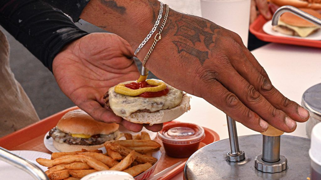 tattooed hand pressing on mustard dispenser for fast food