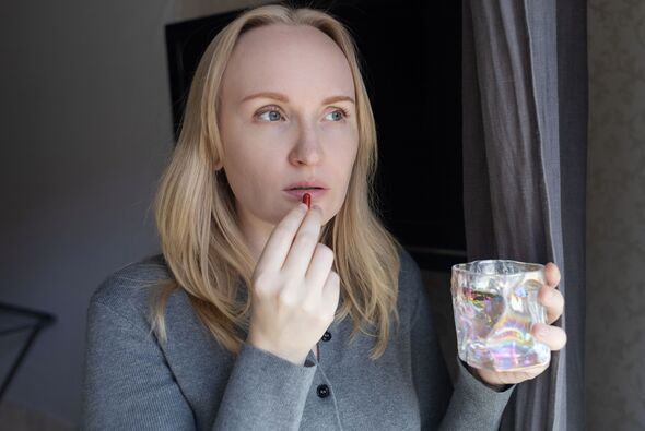 Woman taking iron supplement capsule with glass of water. Female health care, iron deficiency anemia treatment, vitamins and minerals intake for welln Woman taking iron supplement capsule with glass of water. Female health care, iron deficiency anemia treatment, vitamins and minerals intake for welln