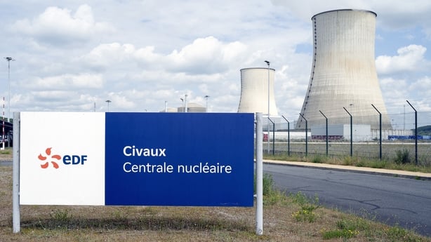 An E.D.F sign reading Civaux Centrale nucleaire stands beside the road in front of the fenced cooling towers of the Civaux nuclear power