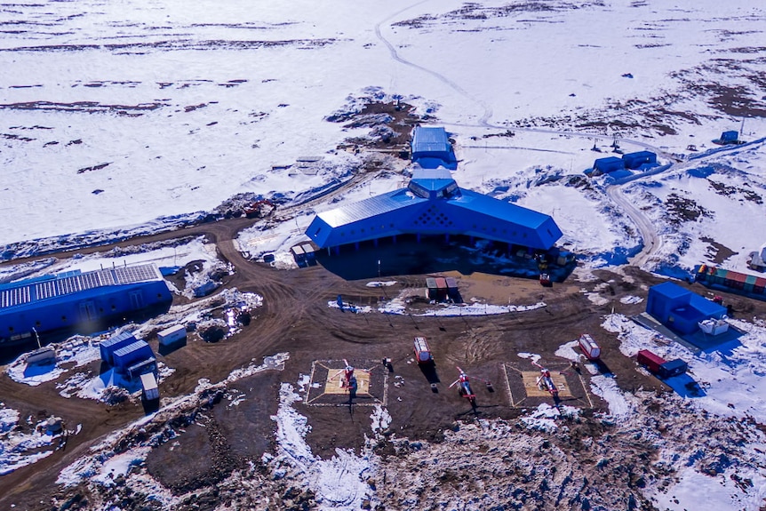 Large, blue, warehouse-style buildings in a snowy, Antarctic landscape.