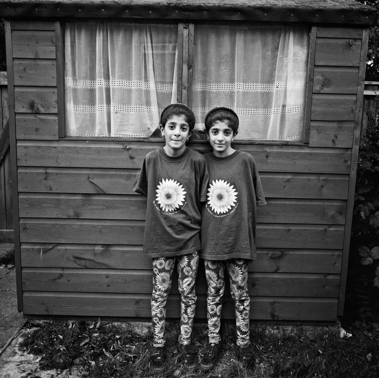 Twin girls Bijli and Bindiya standing in front of a shed.