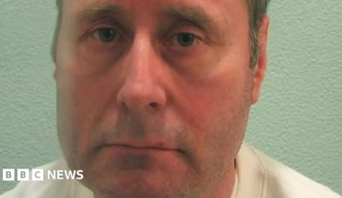 A mugshot of John Worboys. He is staring into the camera, and wearing a white top.