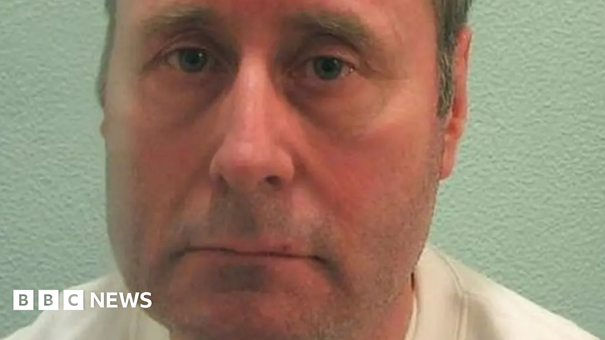 A mugshot of John Worboys. He is staring into the camera, and wearing a white top.