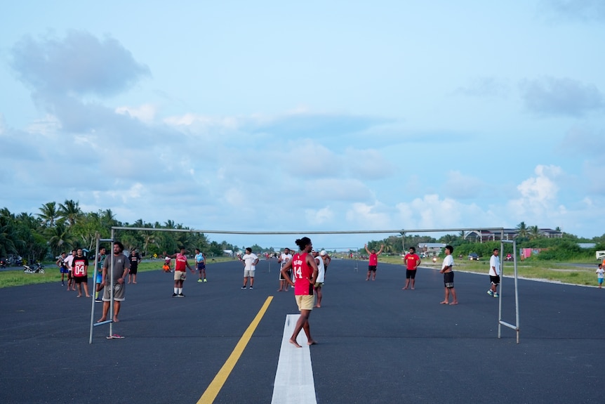 Locals setup a football court on the runway tarmac at sunset.