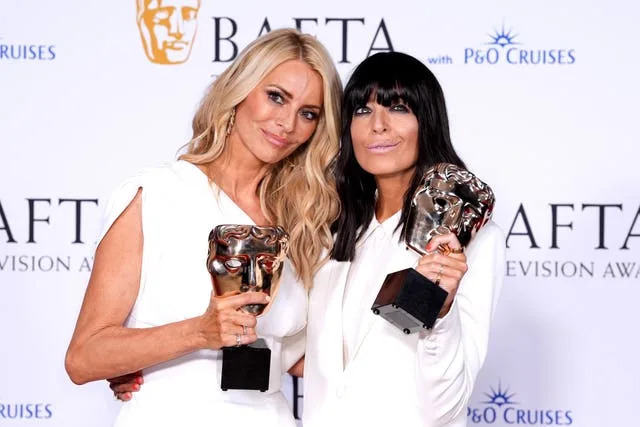 Tess Daly, left, and Claudia Winkleman holding up Baftas