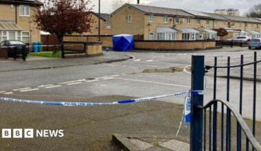 Crime scene on a residential street sealed off with blue-and-white police tape
