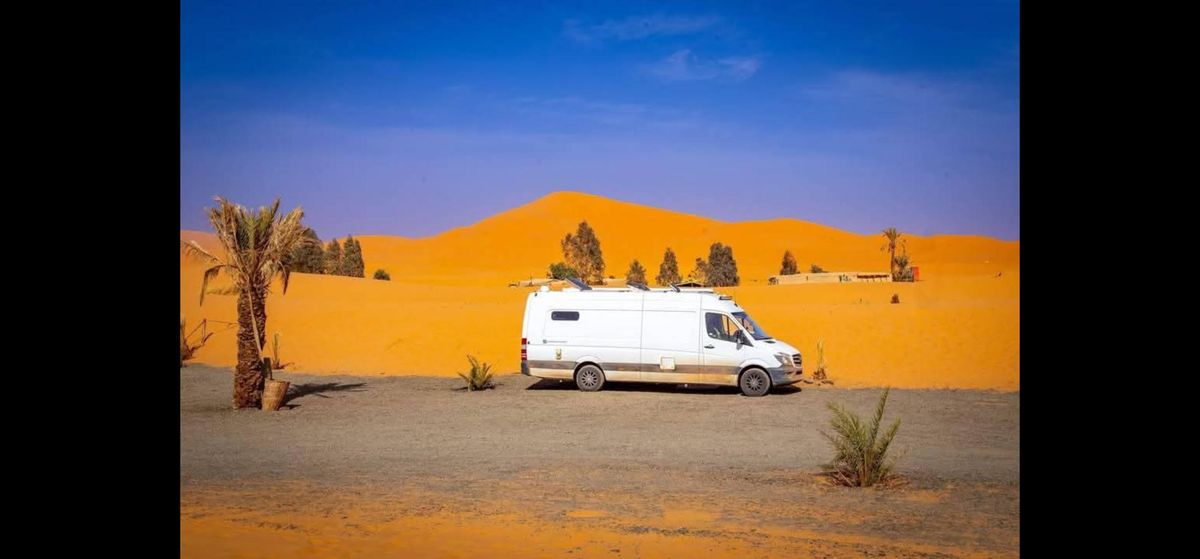 A van parked up on the edge of the Sahara desert