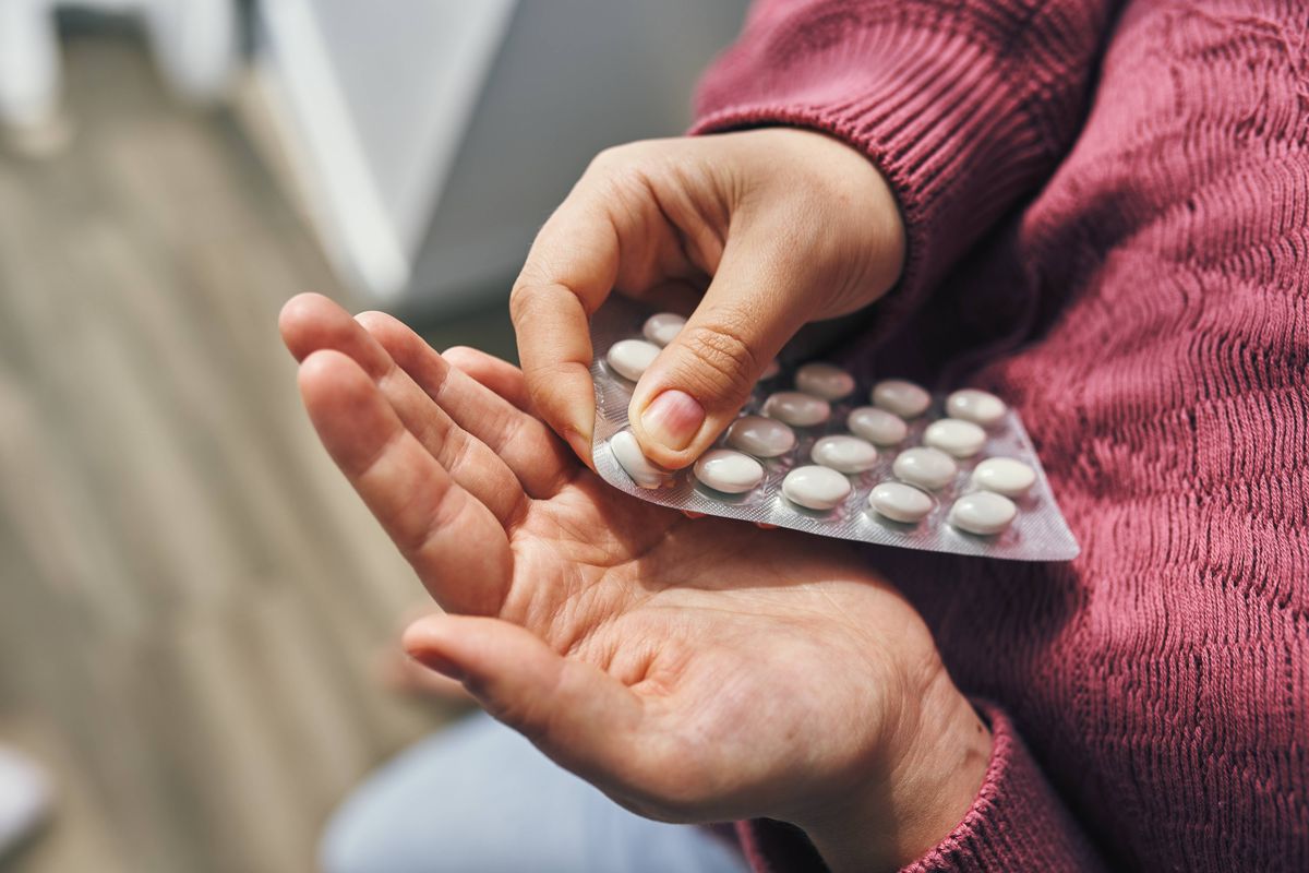 Close perspective of hands carefully holding a blister pack with white pills, emphasizing health and medication concepts.