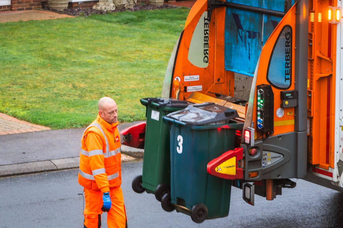 Crawley, UK - 8 January, 2026: elevated view of a garbage truck and a waste collection worker loading trash bins into the truck on a residential street in southeast England.