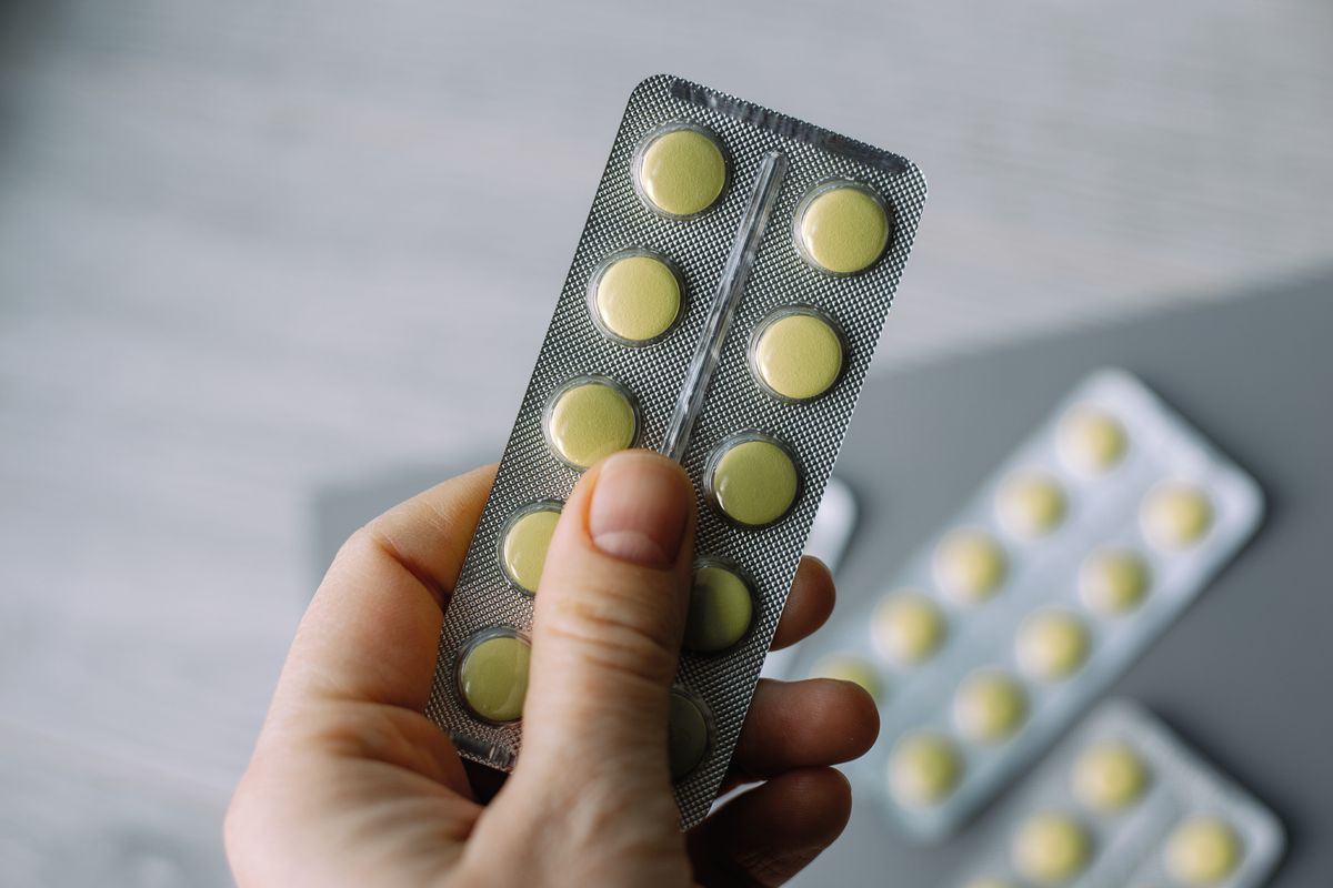 Female hand hold pack of yellow tablet blisters. Panacea, life save service, prescribe medicament, legal drug store, disease healing, blood pressure concept.