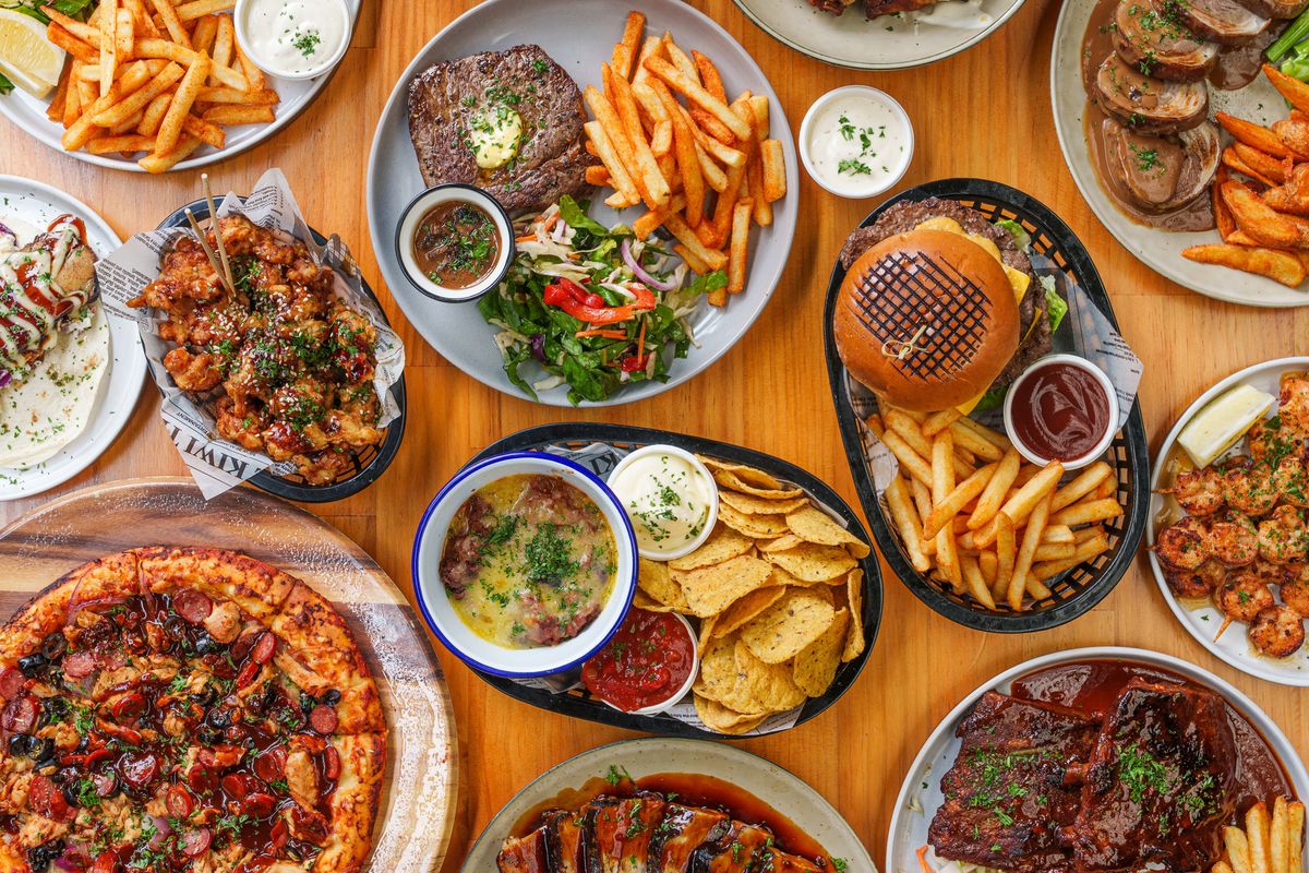 Table top of variety of assorted dishes of pizzas, burgers, fries, sauces