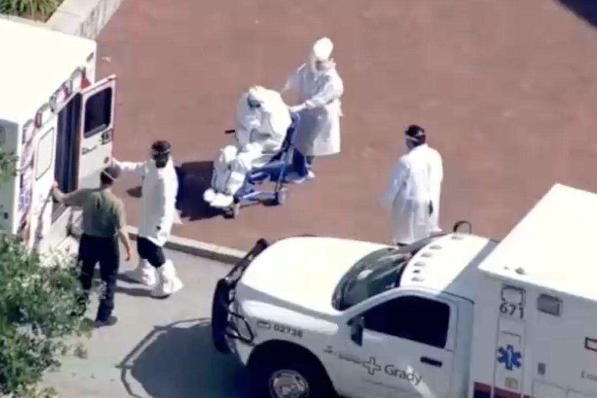 Healthcare workers in full hazmat gear greet one of the virus-stricken cruise passengers at Emory University Hospital in the US